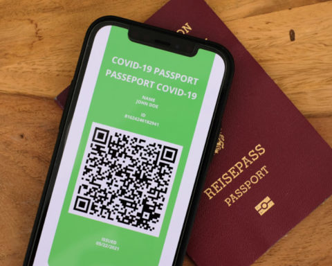 Mobile phone with COVID passport screen and paper passport